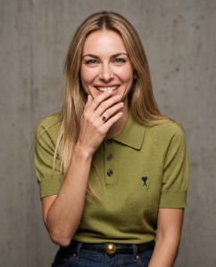 Une jeune femme de 35 ans dans un portrait éditorial serré. Ses cheveux blonds sont en désordre et elle porte exactement la même veste en cuir verte. Sa bouche forme un « o », comme si elle voulait siffler : une expression authentique, légèrement asymétrique, spontanée. Réalisez cette prise de vue comme si elle avait été prise par un photographe professionnel dans un studio aux conditions contrôlées. Utilisez un objectif fixe de 80 mm à f/2,8 : la mise au point se fait précisément sur les yeux et les cils, le reste du visage présentant une transition douce mais toujours nette.